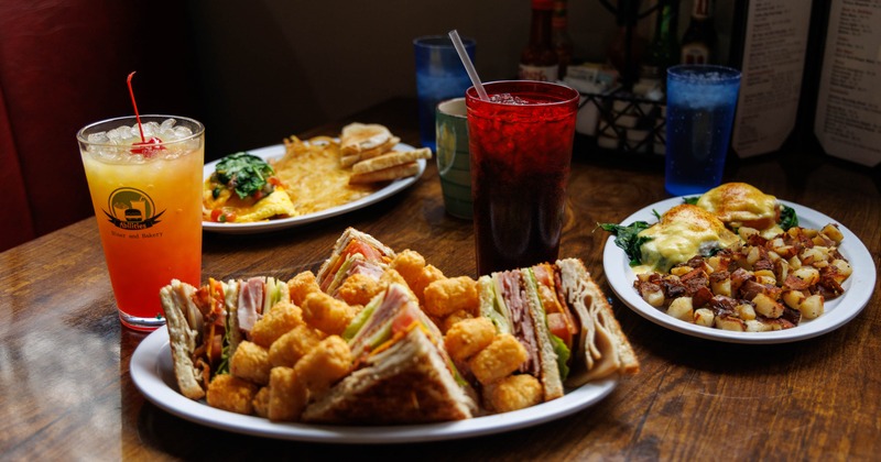 Club sandwich with tater tots, served alongside other dishes and a drink