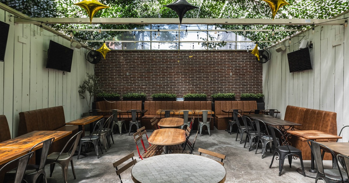 Outdoor patio featuring a brick wall backdrop, string lights booth and table seating