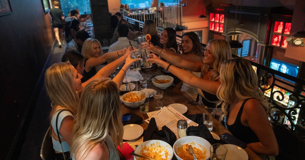 Group of people toasting with drinks at a table with empty plates