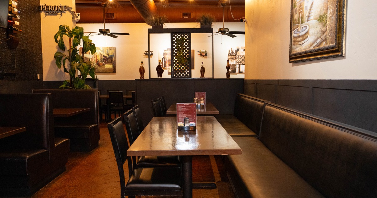 Interior of a restaurant with wooden tables, black seating, wall art, and warm lighting