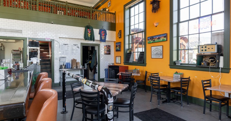 Interior seating area with orange and white walls, a bar, and dining tables