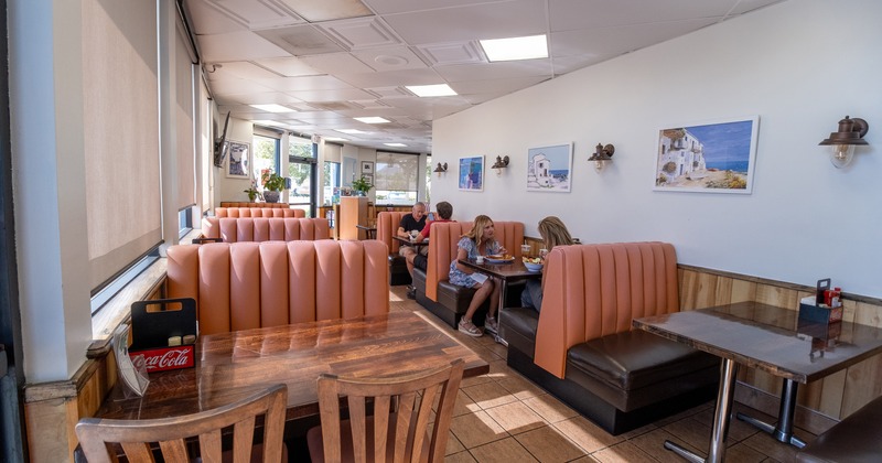 Guests dining in a bright restaurant with tan leather booths