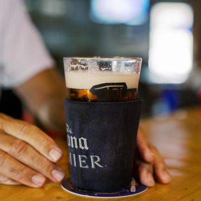 A glass of beer with a cozy.