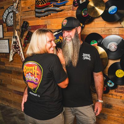 A pair of patrons posing in front of a wall decorated with music memorabilia.