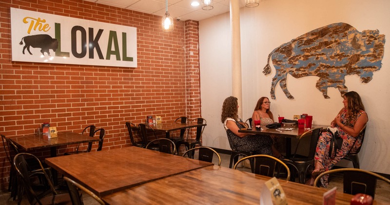 Restaurant interior with guests, business logo sign, and wall art