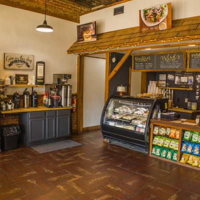 Counter area with wooden paneling, a pastry display case, and a beverage station.