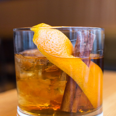 cocktail with orange peel and cinnamon sticks in the glass