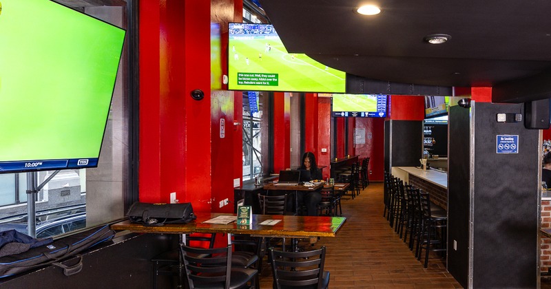 Interior with high-top tables, stools, tilled flor and TV screens