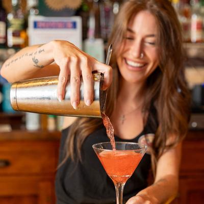 A bartender pouring a glass of Cosmopolitan cocktail.