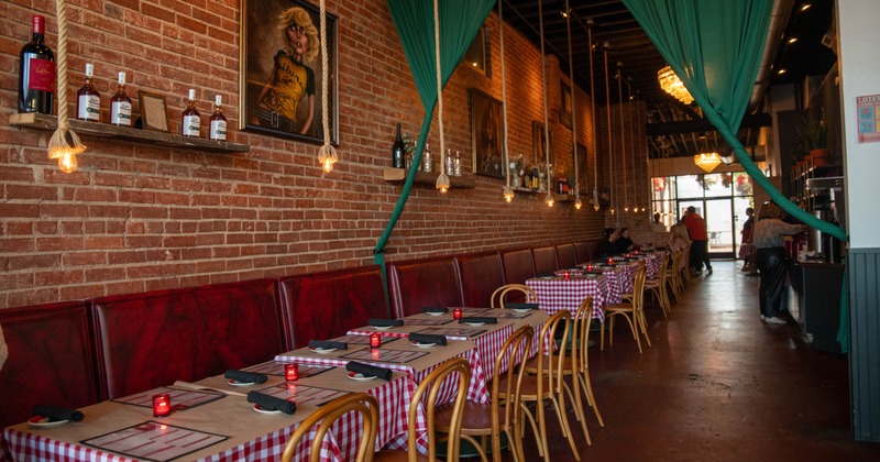Interior, dining area, padded banquette bench with tables and chairs, red brick walls