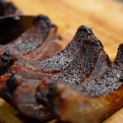 Close-up of smoked barbecue ribs on a wooden cutting board.