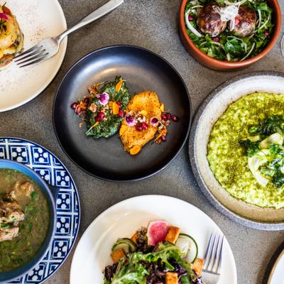 assorted colorful dishes from Supra restaurant arranged on gray table