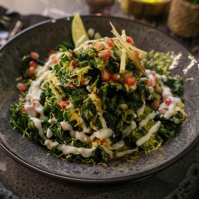 Palak chaat featuring spinach leaves layered with spiced yogurt, chutney, and pomegranate seeds.