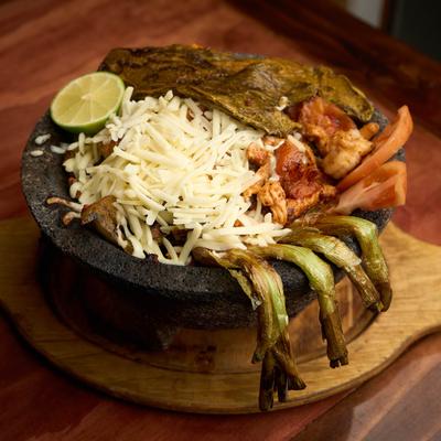 Molcajete with chicken, shrimp, chorizo, cheese, and cactus.