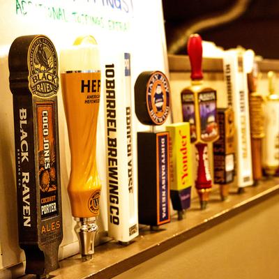 Assorted beer tap handles at a bar.