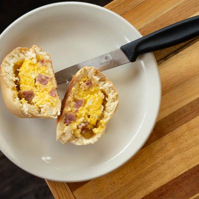 Breakfast kolache cut in half, filled with scrambled eggs, cheese, and ham.