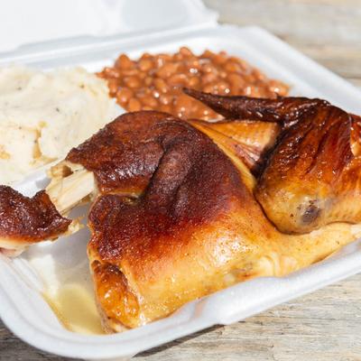 Half chicken with a side of baked beans and mashed potatoes.