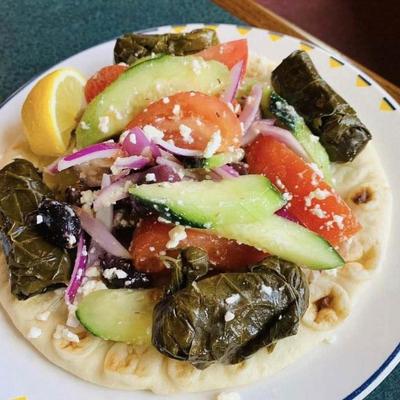 Pita topped with stuffed grape leaves, cucumbers, tomatoes, and feta cheese.