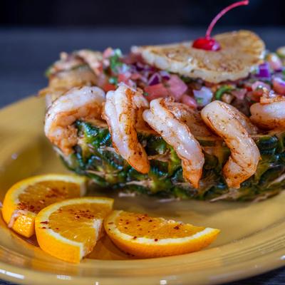 Pineapple shrimp bowl on a plate with orange slices.