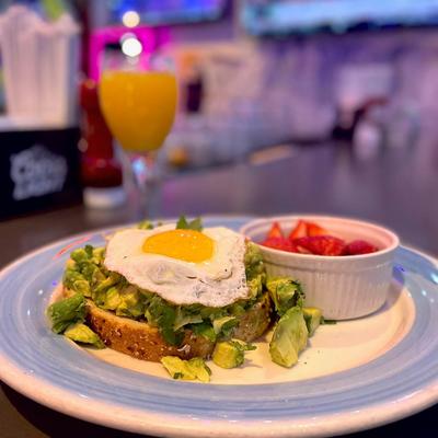 Avocado toast topped with a fried egg, served with strawberries.