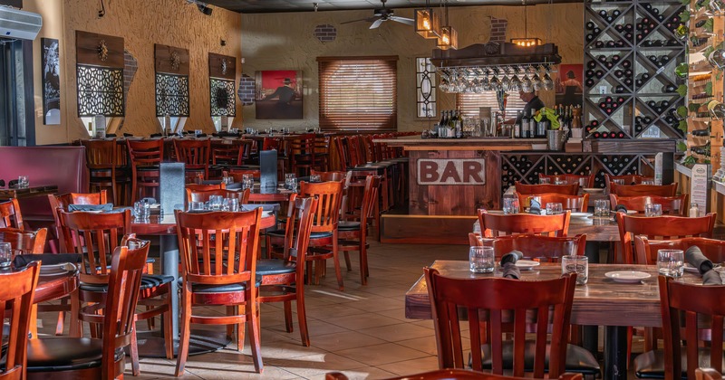 Dining area, tables ready for guests, bar area in the back