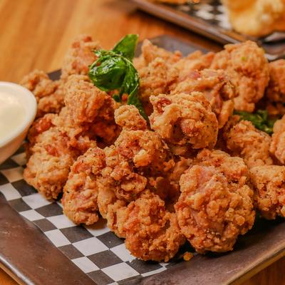 Popcorn chicken served with a side of dipping sauce, close-up.