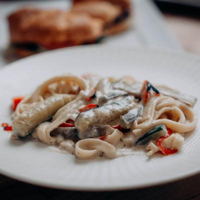 Plate of pasta with a creamy sauce and vegetables.