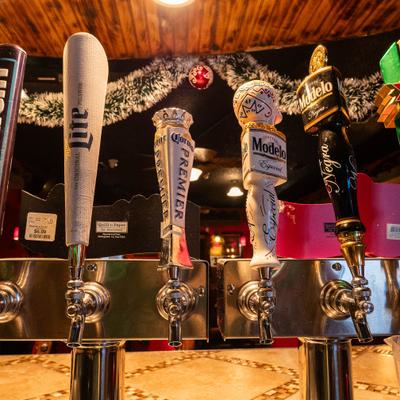Close-up of four beer taps with unique handles featuring various beer brands.