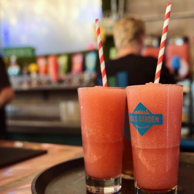 Two pink frozen drinks with straws on a serving tray.