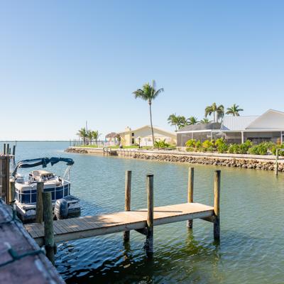 Wooden docks extend into calm canal beside palm lined waterfront homes.