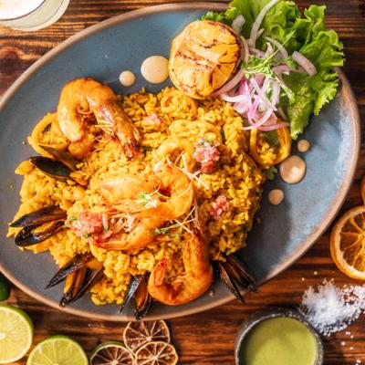 Yellow seafood rice dish with prawns and mussels on a blue plate.