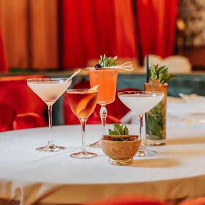Assorted craft cocktails served on a table with fresh herbs and citrus garnish..