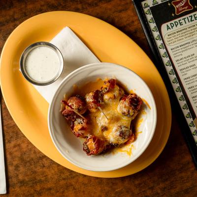 Bacon wrapped tater tots with sauce for dipping.