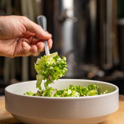 A forkful of salad being pulled from a large bowl.