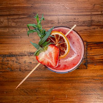 Cocktail garnished with a fresh strawberry, a dried lemon slice, and mint.