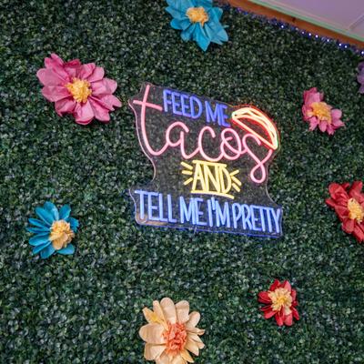 Neon signage prominently displayed on a green foliage wall.
