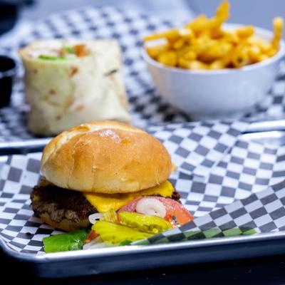 Cheeseburger served on a tray, alongside wrap served with fries.