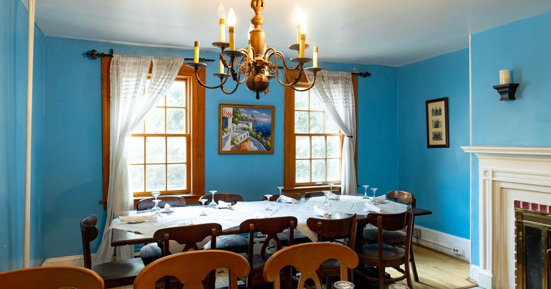 Interior, set dining table, fireplace, blue walls, two curtained windows