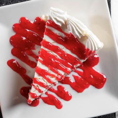A slice of cheesecake drizzled with raspberry bourbon sauce.