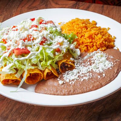 Flautas topped with lettuce and crema, served with rice and refried beans.