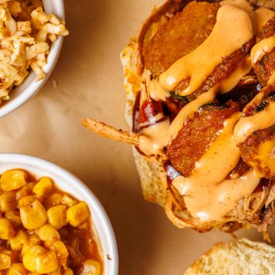 Fried Pickle Sammy with Cajun corn and coleslaw on the side, close up.