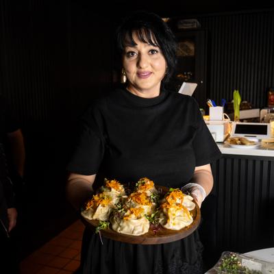 A waitperson holds a plate of manti dumplings.