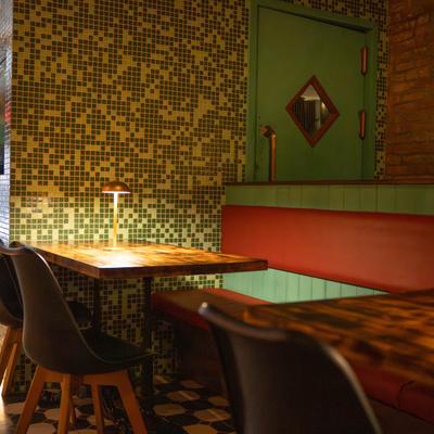 Interior, green mosaic walls with red booth seating and wooden tables.
