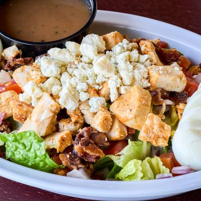 Cobb salad with chicken, bacon, cheese, hard-boiled egg, and dressing.