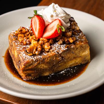 Banana bread pudding topped with walnuts, whipped cream and strawberries.