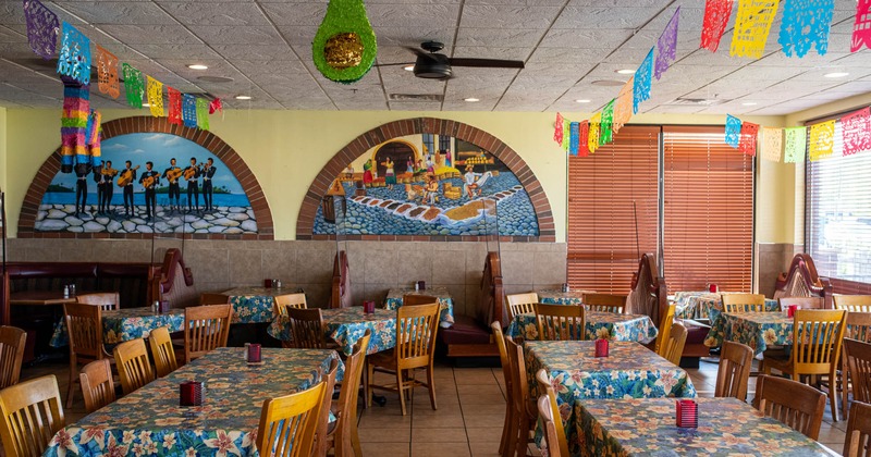 Interior, dining area, tables with floral pattern cloths and wooden chairs, tile flooring