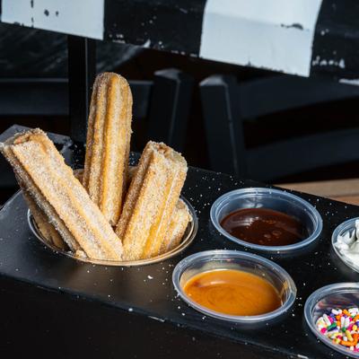 Cart shaped platter with three churros and dipping sauces.