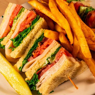 Smoked Turkey panini served with pickle and fries.