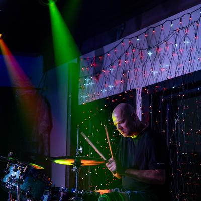 Band drummer, green and red lighting.