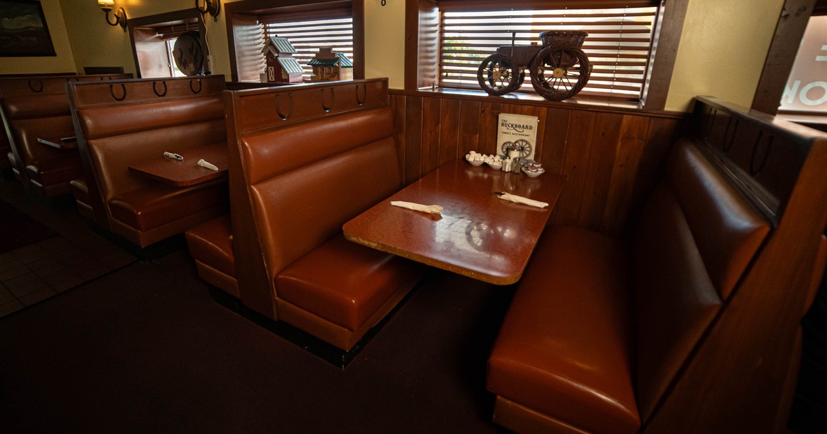 Interior of a restaurant with brown leather booth seating, wooden paneling, and window blinds